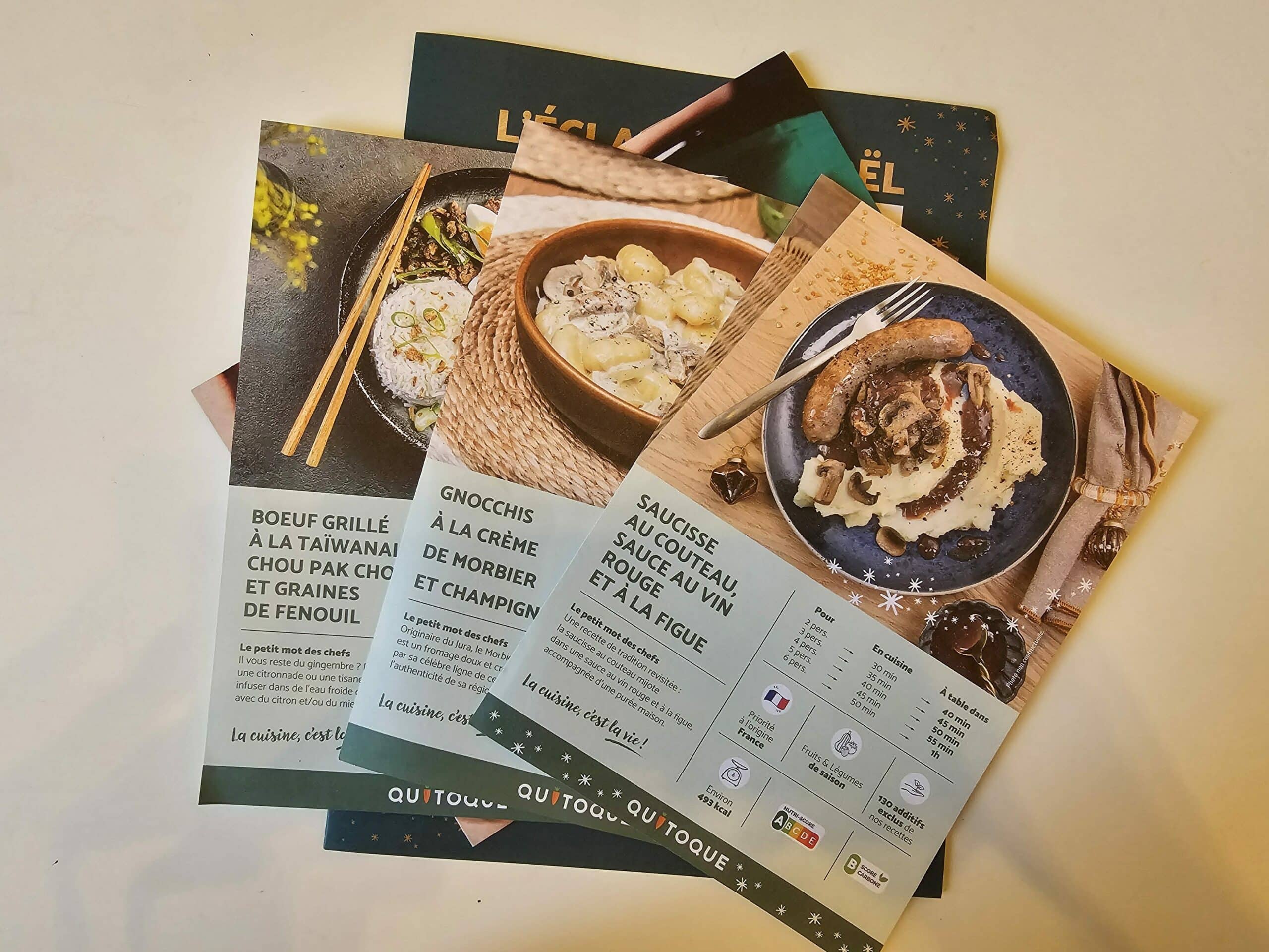 Photo d’une cuisine conviviale avec une box Quitoque posée sur le plan de travail, entourée de légumes de saison, d’herbes fraîches et de fiches recettes. L’image illustre les valeurs de la marque Quitoque France : produits locaux, saisonnalité et cuisine maison simple.