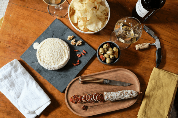 Sélection de fromages artisanaux accompagnés d’une bouteille de vin pour illustrer la box Vin et Fromage de La Boite du Fromager.