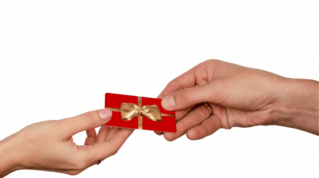 Carte cadeau tenue dans une main avec un carnet et un stylo, symbolisant la liberté de choix et le plaisir de décider soi même de son cadeau au bon moment.