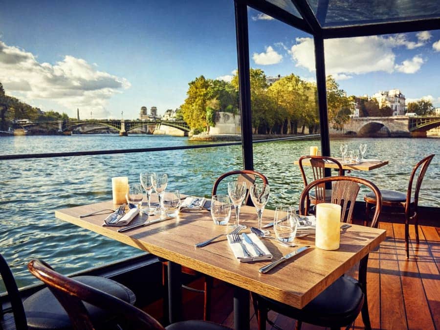Salle de restaurant à bord d’un bateau pendant un dîner croisière sur la Seine avec vue sur les monuments de Paris