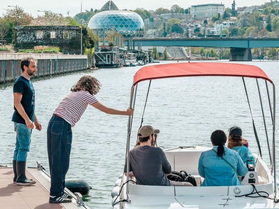 Petit bateau électrique loué par des visiteurs naviguant sur un canal parisien pour une balade en bateau à Paris