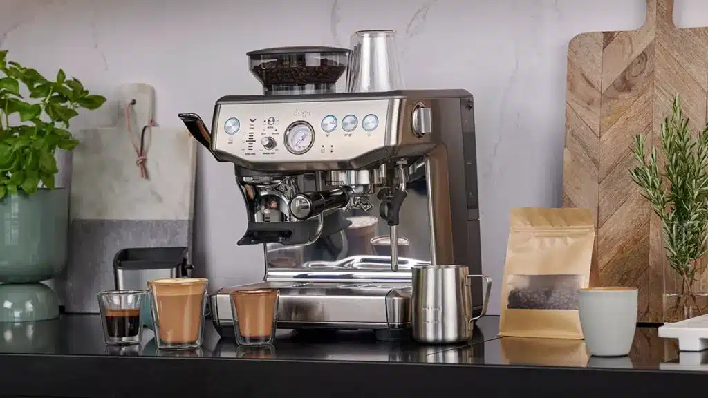 La Sage Barista Express SES875 en acier inoxydable brossé vue de face, avec son moulin conique intégré sur le côté gauche, sa buse vapeur manuelle à droite et son portafilter en chrome installé dans la tête de groupe