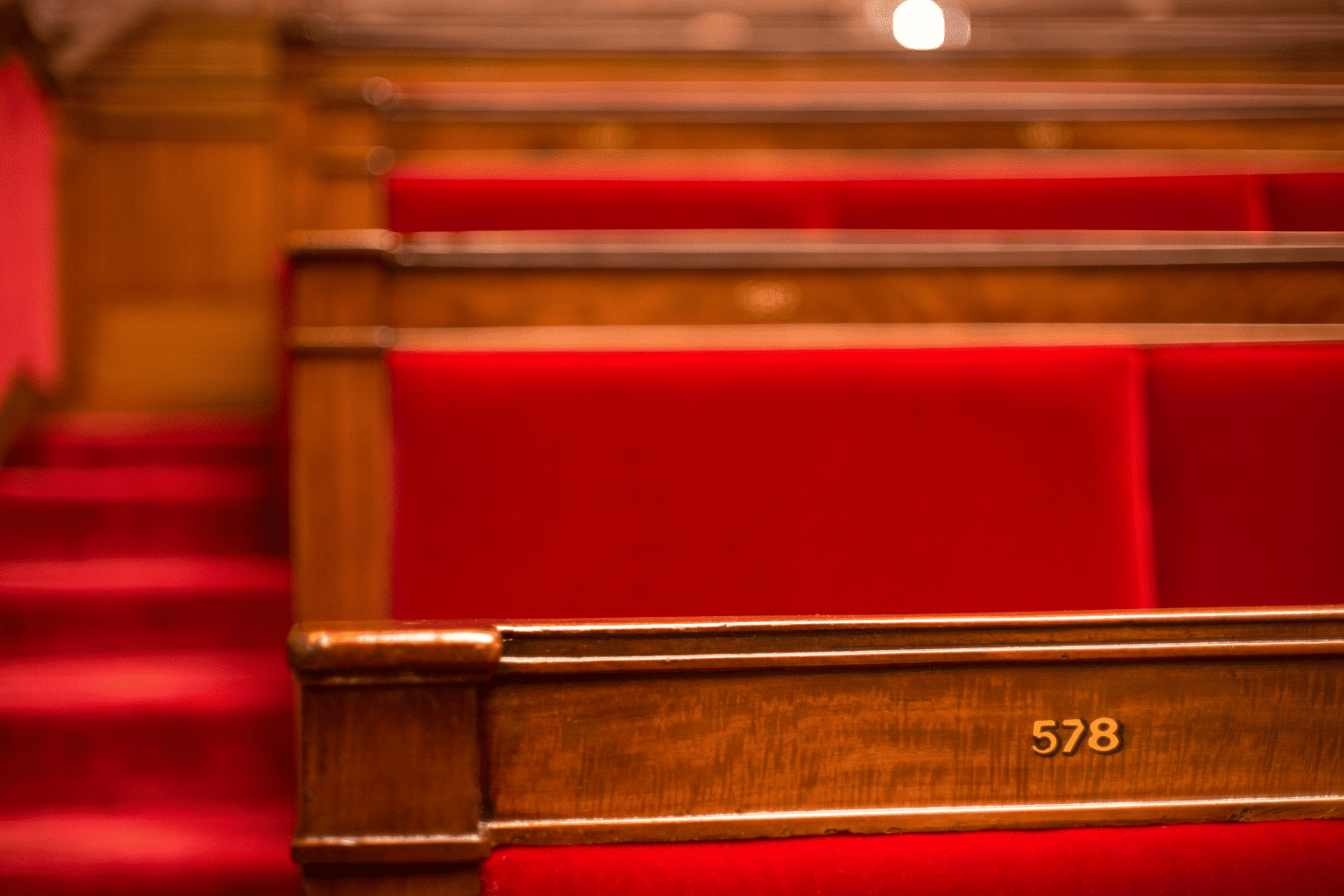 Hémicycle de l'Assemblée nationale française lors d'une séance de vote, travées et pupitres sous lumière dorée