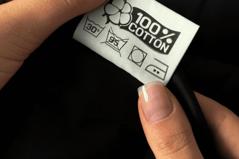 Étiquette de composition cousue à l'intérieur d'un vêtement, mentions coton 100%, made in Portugal, fond de tissu blanc