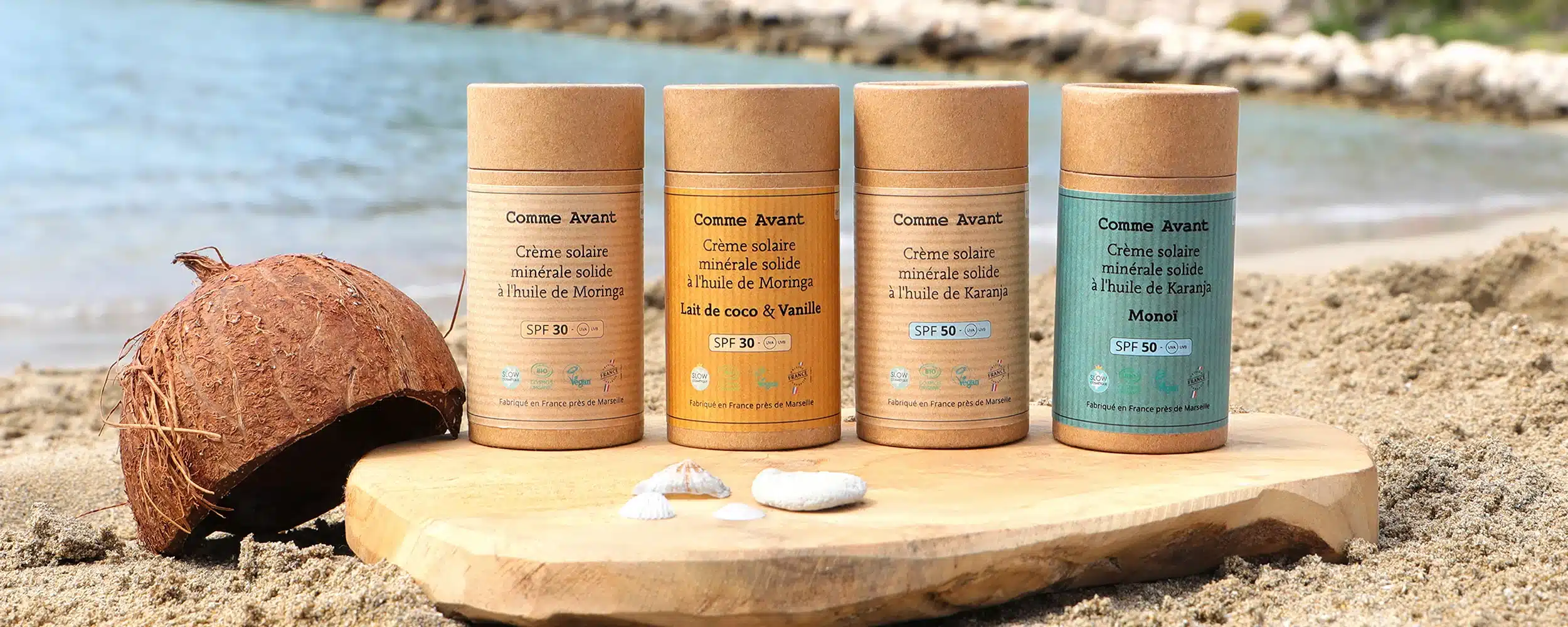 le stick de crème solaire SPF50 Comme Avant posé au milieu de mon sac de plage, entre une serviette et une paire de lunettes de soleil, pris en photo un matin avant de partir. C’est le format que j’emmène partout depuis cet été, y compris en bagage cabine puisqu’il est solide. On distingue la texture légèrement crayeuse du stick qui dépasse du tube carton.