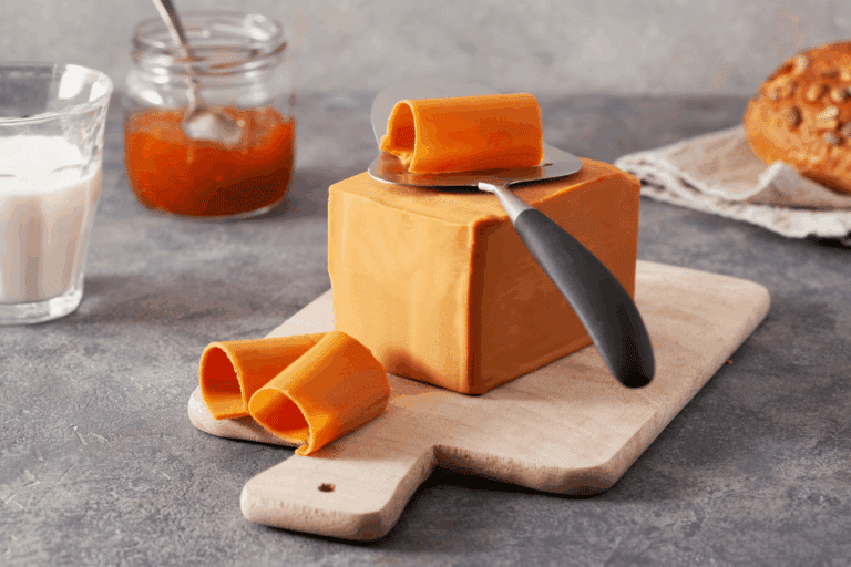 Tranches fines de brunost, fromage brun norvégien, découpées à l'ostehøvel sur une planche en bois