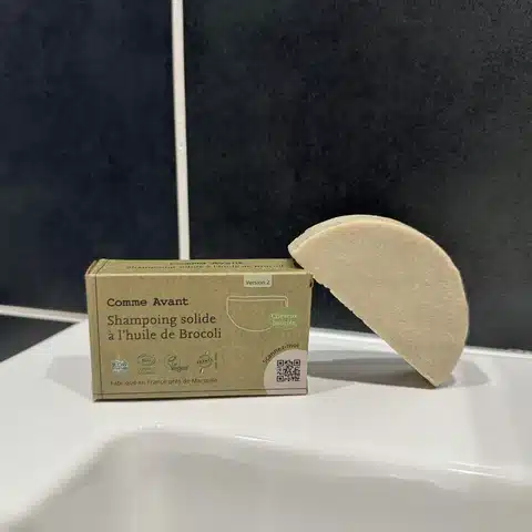 gros plan sur la surface du galet légèrement humide, où l’on distingue de petites variations de texture liées à la présence d’huile de brocoli dans la formule, contrairement à un galet parfaitement lisse et uniforme.