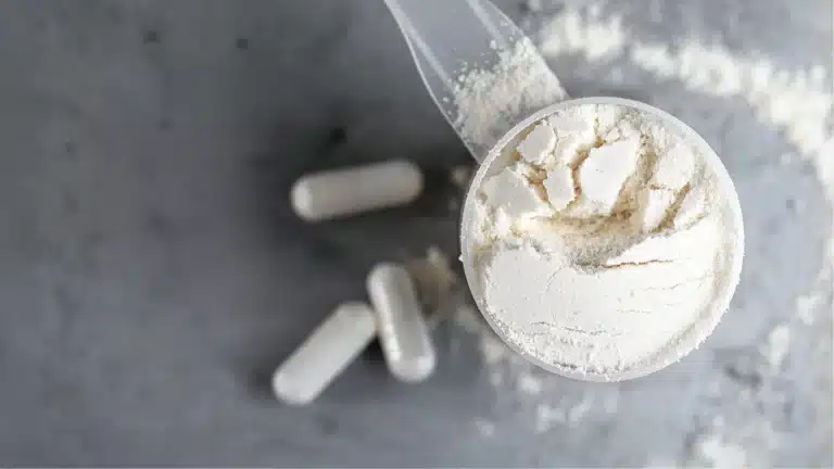 mon shaker vide posé à côté du pilulier de créatine Creapure Dynveo, juste après ma séance du jeudi soir. J’ai pris l’habitude de diluer ma dose directement dans l’eau du shaker plutôt que de prendre les gélules, parce que ça me permet de la boire en rentrant de la salle, pendant que je range mes affaires. On voit le pot de 250g de poudre blanche presque entamé, posé sur le plan de travail à côté d’une banane, mon en-cas habituel après l’entraînement.