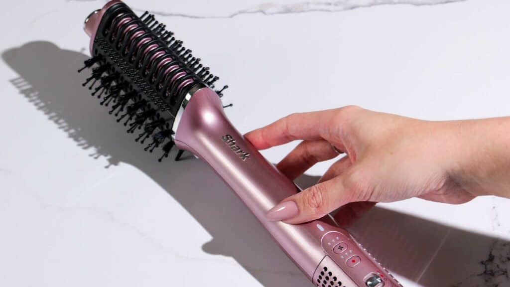 photo de mes mains qui tiennent une mèche avec la brosse du Shark Glossi pour illustrer mes astuces