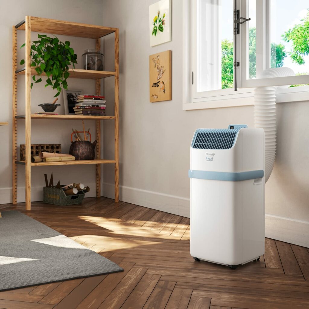 Climatiseur mobile De’Longhi Pinguino installé près d’une fenêtre avec son tuyau d’évacuation, pour montrer comment rafraîchir une pièce sans travaux